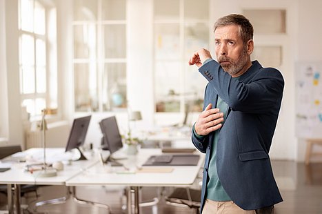 Mann in Büro mit Husten