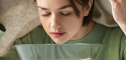 Junge Frau inhaliert heißen Wasserdampf.