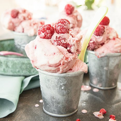 Selbstgemachtes Himbeereis mit frischen Himbeeren in einer Schale.
